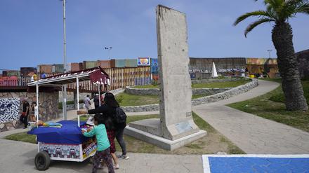 Eine Familie schiebt einen Imbisswagen an einem Stück der Berliner Mauer vorbei, die in der Nähe der Grenzmauer, die die Vereinigten Staaten von Mexiko trennt, ausgestellt ist.