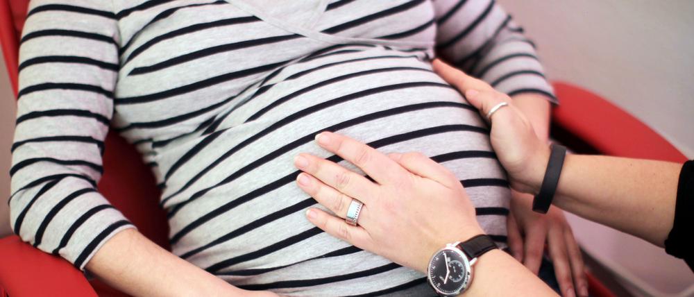 Eine Hebamme untersucht eine schwangere Frau. 