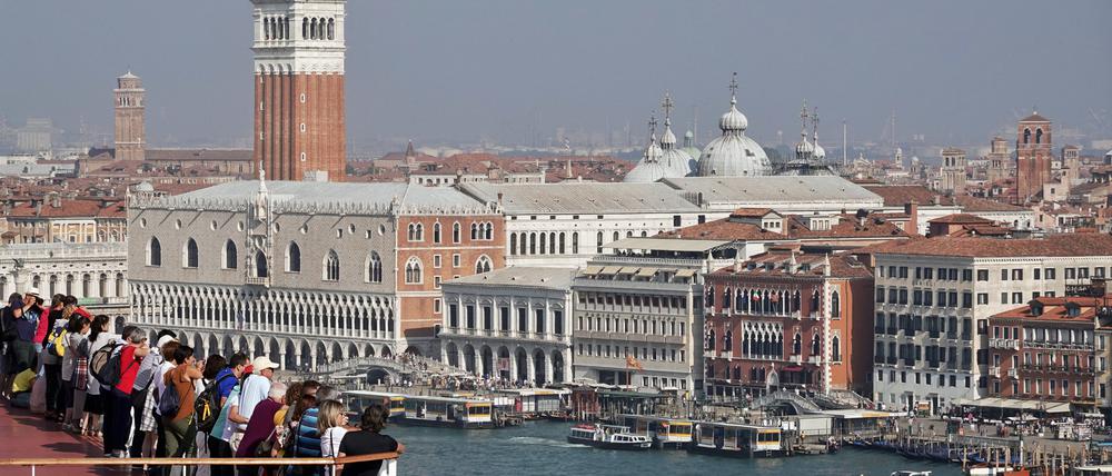 Touristen fahren an Bord eines Kreuzfahrtschiffes am Markusplatz und dem Dogenpalast vorbei (Symbolbild).