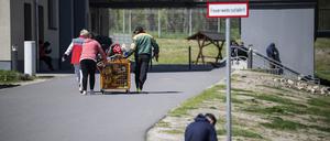 Menschen schieben einen Wagen mit Spielzeug über das Gelände der Erstaufnahme-Einrichtung (EAE) des Landes Brandenburg in Eisenhüttenstadt. 