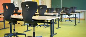 Die Stühle sind in einem leeren Klassenzimmer auf die Schulbänke gestellt.