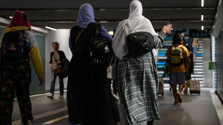 Frauen tragen Abayas, während sie durch eine Unterführung gehen. 