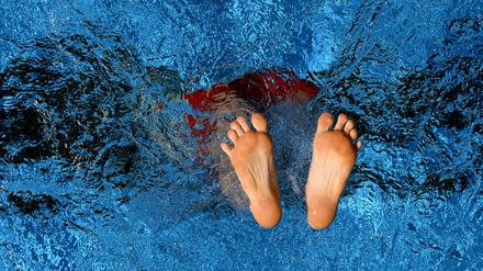 Ein Schwimmer springt ins erfrischende Schwimmbecken: Nur noch seine Füße sind zu sehen.