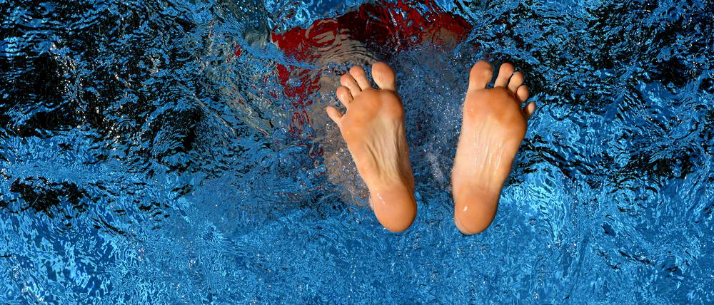 Ein Schwimmer springt ins erfrischende Schwimmbecken: Nur noch seine Füße sind zu sehen.