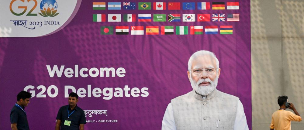 Sicherheitskräfte stehen Wache in der Nähe einer G20-Kommunikationstafel mit dem Konterfei des indischen Premierministers Narendra Modi im internationalen Medienzentrum des G20-Treffpunkts.