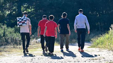 06.09.2023, Brandenburg, Eisenhüttenstadt: Migranten kommen von der Erstaufnahme-Einrichtungen (EAE) des Landes Brandenburg in Eisenhüttenstadt und gehen durch einen Park. Die Ministerpräsidenten und -präsidentinnen der 16 Bundesländer reisen an diesem Mittwoch nach Brüssel. Thema der zweitägigen Länderkonferenz ist auch die Aufnahme von Flüchtlingen. Foto: Patrick Pleul/dpa +++ dpa-Bildfunk +++
