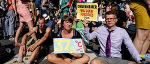 Hunderte Klimaaktivisten mit Protestschildern und Flaggen auf einer Autobahn in Den Haag. 