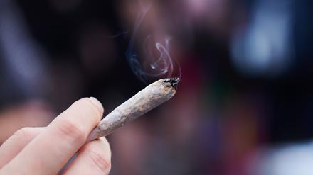 Eine Frau hält einen Joint mit Cannabis in der Hand. 