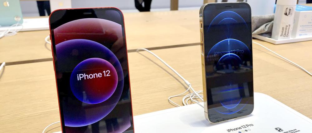 Ein iPhone 12 (l) und ein iPhone 12 Pro stehen in einem Apple Store auf einem Tisch.