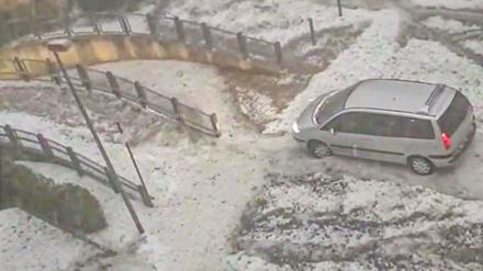 Ein Van fährt nach einem heftigen Hagelschauer über einen winterlich anmutenden Parkplatz.