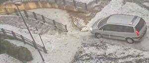 Ein Van fährt nach einem heftigen Hagelschauer über einen winterlich anmutenden Parkplatz.