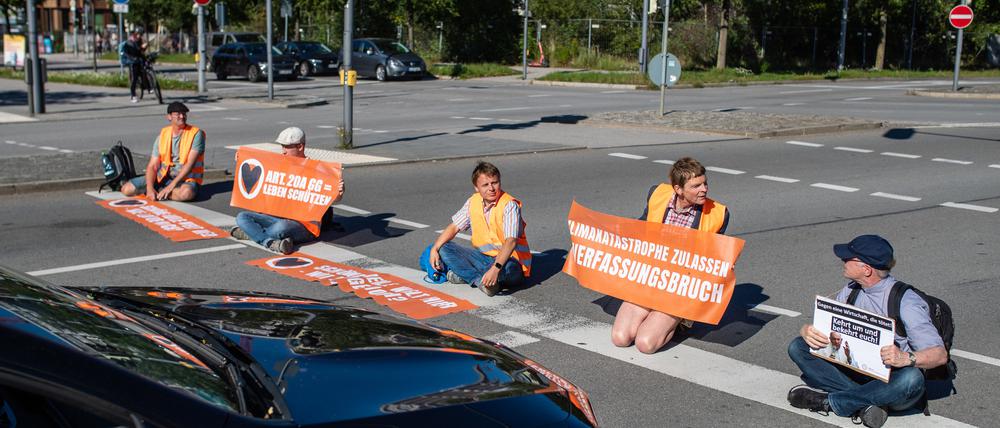 Klimaaktivisten der ·Letzten Generation· bilden in München eine Straßenblockade.