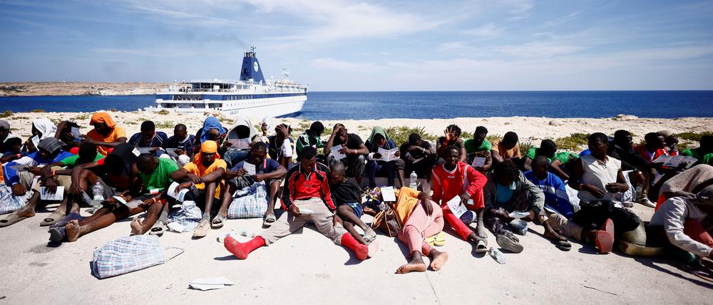 Migranten warten in der Nähe des Hafens auf der sizilianischen Insel Lampedusa auf ihre Überführung zum Festland, Italien, 14. September 2023.