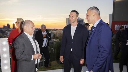 14.09.2023, Berlin: Bundeskanzler Olaf Scholz (SPD, l) unterhält sich mit Vitali Klitschko (r), Bürgermeister von Kiew, und seinem Bruder Wladimir (M) bei der Veranstaltung «BILD100» der BILD und BILD am SONNTAG auf dem Dach des Axel-Springer-Neubaus. Foto: Christoph Soeder/dpa +++ dpa-Bildfunk +++