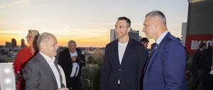 14.09.2023, Berlin: Bundeskanzler Olaf Scholz (SPD, l) unterhält sich mit Vitali Klitschko (r), Bürgermeister von Kiew, und seinem Bruder Wladimir (M) bei der Veranstaltung «BILD100» der BILD und BILD am SONNTAG auf dem Dach des Axel-Springer-Neubaus. Foto: Christoph Soeder/dpa +++ dpa-Bildfunk +++