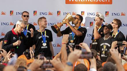 Alba-Kapitän Johannes Thiemann hält beim Empfang in Berlin die WM-Trophäe in Händen.