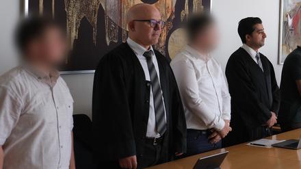 Zwei Angeklagte stehen mit ihren Anwälten Cem Kilic (2.v.l.) und Zubair Khan (r) im Gerichtssaal. 