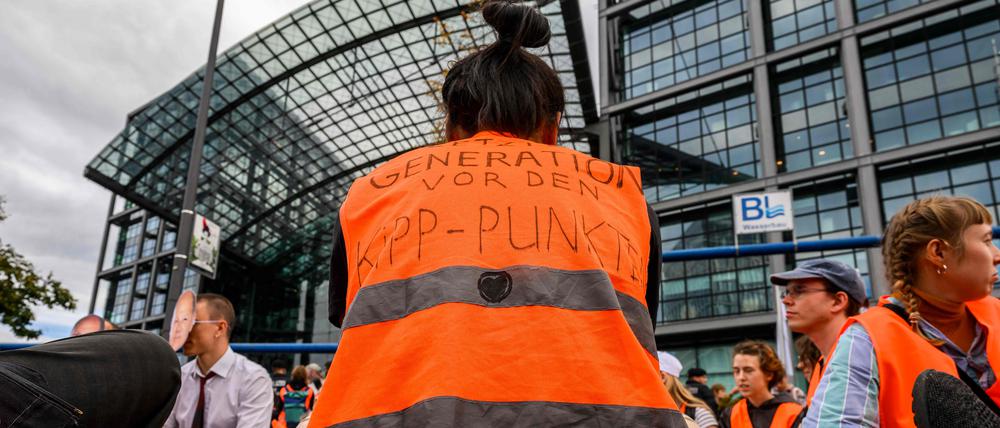 Eine Klimaaktivistin der Gruppe „Letzte Generation“ trägt eine Warnweste mit der Aufschrift: „Before the tipping point“ („Vor dem Kipppunkt“), als sie am 13. September 2023 den Verkehr vor dem Hauptbahnhof in Berlin blockiert.
