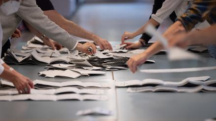 Wahlhelfer und Wahlhelferinnen zählen in einem Wahllokal Stimmzettel für die Bundestagswahl. 