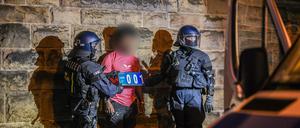 Ein Mann (M), der zu einer Gruppe von Menschen gehört, die nach Ausschreitungen bei einer Eritrea-Veranstaltung von Polizeikräften eingekesselt wurden, wird von Polizisten abgeführt. 
