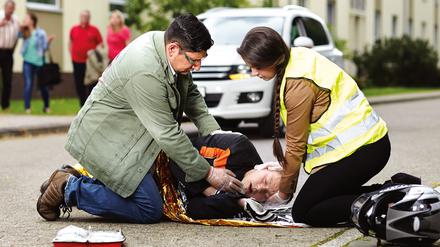 Nach einem Unfall legen Helfer den Betroffenen in die stabile Seitenlage, überprüfen die Atmung und beginnen gegebenenfalls mit einer Herzdruckmassage.
