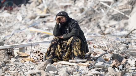 Eine Frau sitzt im türkischen Antalya zwischen Trümmern und beobachtet die Bergung von Opfern. Am 6. Februar 2023  bebte die Erde in der Türkei mit einer Stärke von knapp 8 von 10 Punkten auf der Richterskala.