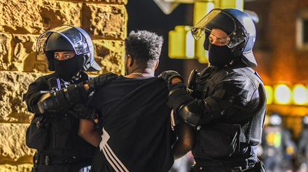 Ein Mann, der zu einer Gruppe von Menschen gehört, die nach Ausschreitungen bei einer Eritrea-Veranstaltung von Polizeikräften eingekesselt wurden, wird von Polizisten abgeführt. 