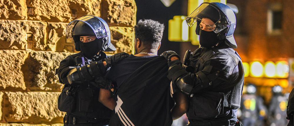 Ein Mann, der zu einer Gruppe von Menschen gehört, die nach Ausschreitungen bei einer Eritrea-Veranstaltung von Polizeikräften eingekesselt wurden, wird von Polizisten abgeführt.