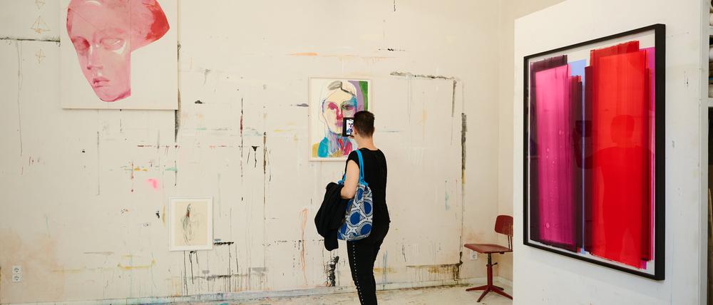 Frauen-Porträts der Künstlerin Tina Berning neben einem Werk von Julio Rondo im Open Studio, der Werkstatt der Künstlerin. 