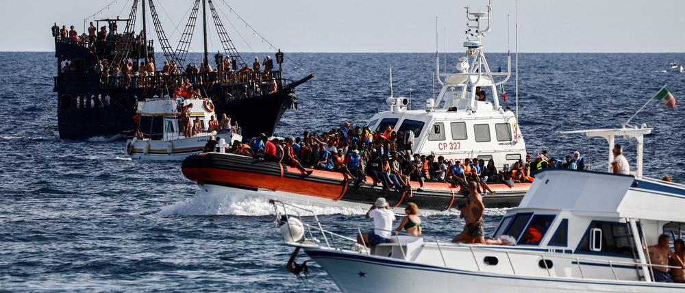 Zwischen Touristenbooten bringt ein Schiff der italienischen Küstenwache gerettete Migranten zur Mittelmeerinsel Lampedusa.