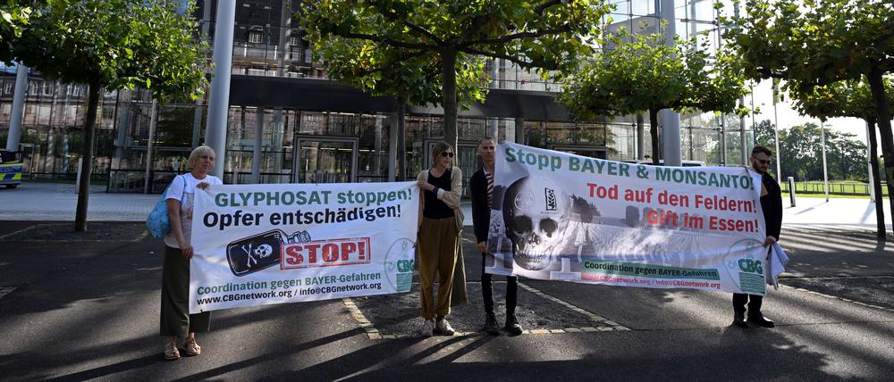 14.09.2023, Nordrhein-Westfalen, Leverkusen: Nicht alle sind für eine Verlängerung der Zulassung: vier Personen halten vor der Konzernzentrale von Baye Banner in den Händen. Die Aktion richtet sich gegen die Verlängerung der EU-Zulassung des Pestizids Glyphosat. 