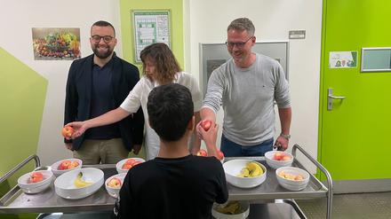 Kurt, Rehm-Zimmer und Doerwald (von links) verteilen Obst an Schüler.