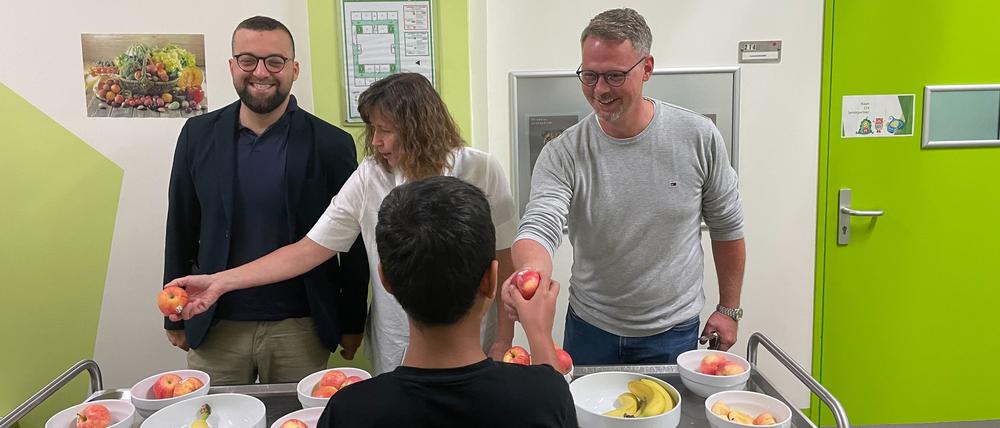 Kurt, Rehm-Zimmer und Doerwald (von links) verteilen Obst an Schüler.