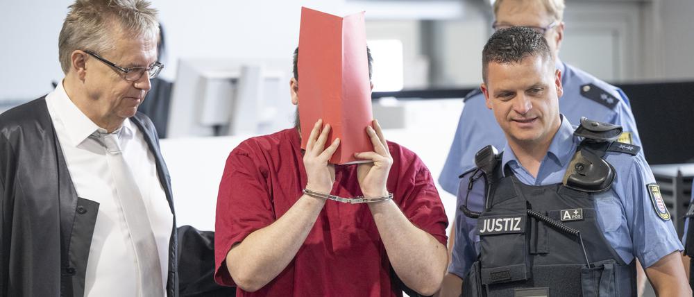 Der Angeklagte (2.v.l.) wird von Justizwachtmeistern in den Verhandlungssaal gebracht. Die Staatsanwaltschaft wirft dem zum Tatzeitpunkt 30-Jährigen vor, die 14 Jahre alte Schülerin Ayleen aus dem südbadischen Gottenheim in Baden-Württemberg im Juli 2022 umgebracht zu haben.