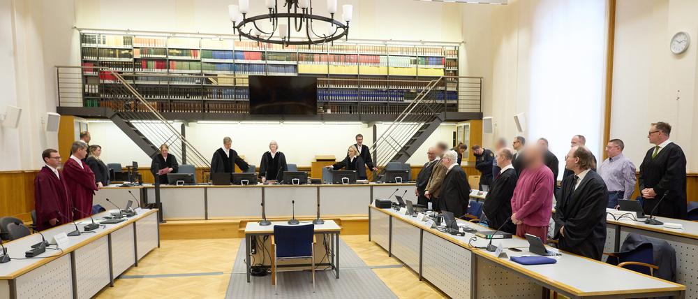 Die Mitglieder der Terrorgruppe „Vereinte Patrioten“ stehen im Verhandlungssaal zwischen ihren Anwälten. (Archivbild)