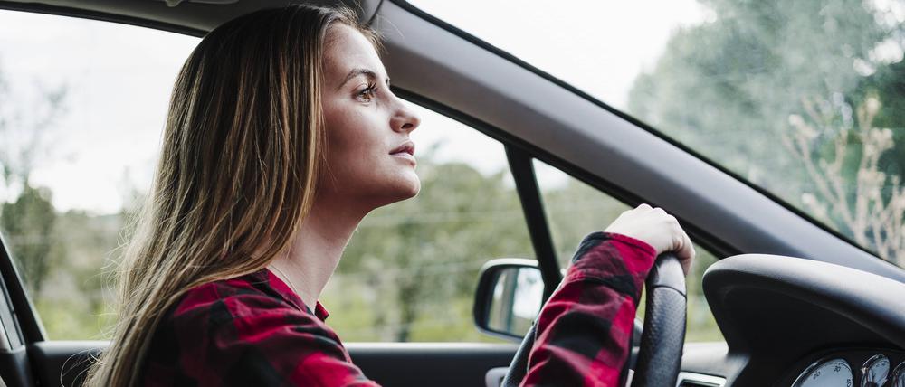 Eine junge Fahranfängerin fährt in einem Auto.