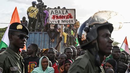 Anhänger des Nationalen Rates für den Schutz des Vaterlandes (CNSP) von Niger halten ein Plakat, während Menschen vor dem nigrischen und französischen Luftwaffenstützpunkt protestieren, um den Abzug der französischen Armee aus Niger zu fordern, in Niamey am 16. September 2023. 