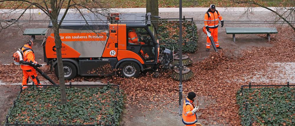 Mitarbeiter der Straßenreinigung entsorgen Herbstlaub. 