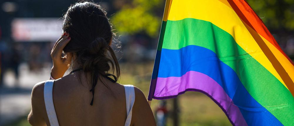 Eine Frau hält eine Regenbogenfahne.  