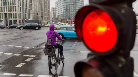 Ein Radfahrer steht an einer roten Fahrradapmel am Potsdamer Platz.