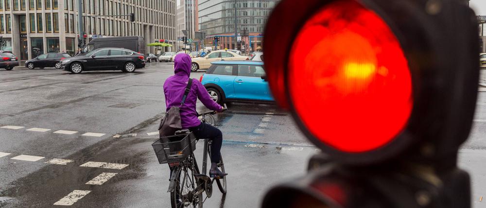 Ein Radfahrer steht an einer roten Fahrradapmel am Potsdamer Platz.