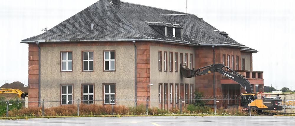 Ein Bagger steht mit umgedrehter Schaufel an dem zum Abriss vorgesehenen ehemaligen Generalshotel auf dem Gelände des Flughafens Berlin Brandenburg (BER).