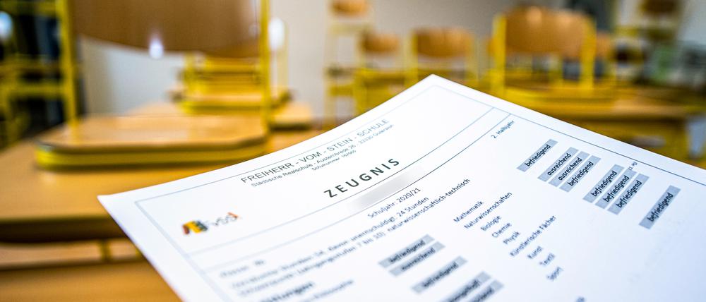 Eine Klassenlehrerin hält das Zeugnis eines Schülers einer Schule in Gütersloh hoch.