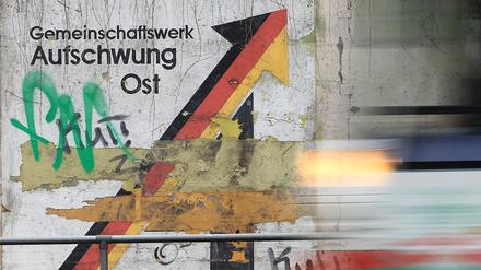 ARCHIV - 19.11.2013, Sachsen-Anhalt, Magdeburg: Am Schriftzug «Gemeinschaftswerk Aufschwung Ost» rollt eine Straßenbahn vorbei. Die Lebensverhältnisse gleichen sich 33 Jahre nach der Deutschen Einheit langsam weiter an, doch sind Löhne und Wirtschaftskraft in Ostdeutschland immer noch niedriger als im Westen. 