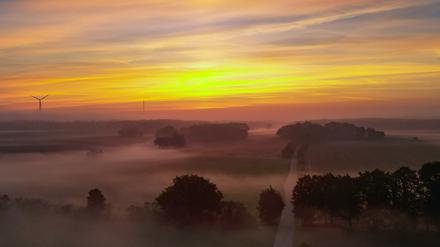25.09.2023, Brandenburg, Sieversdorf: Der Sonnenaufgang leuchtet über der vom Morgennebel verschleierten Landschaft (Luftaufnahme mit einer Drohne). Foto: Patrick Pleul/dpa +++ dpa-Bildfunk +++