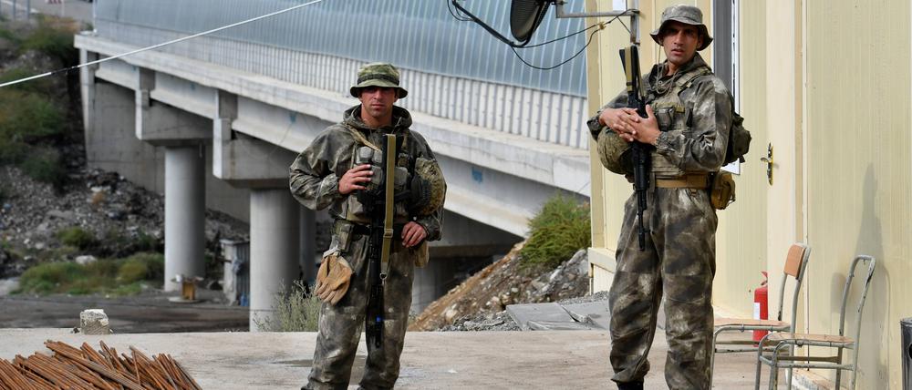 26.09.2023: Aserbaidschanische Soldaten stehen Wache, als Flüchtlinge aus Berg-Karabach den Kontrollpunkt Lachin passieren.