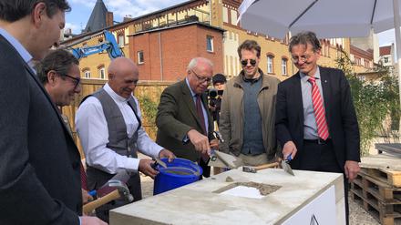Bauwert-Vorstand Jürgen Leibfried, Baustadtrat Florian Schmidt und Bausenator Christian Gaebler (von der Mitte nach rechts) legen symbolisch den Grundstein. 
