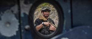Ein Angehöriger einer Spezialeinheit der kosovarischen Polizei steht am 27. September 2023 hinter der von Kugeln beschädigten Tür eines gepanzerten Fahrzeugs in der Nähe des Banjska-Klosters in Banjska im Norden des Kosovo, etwa 15 km von der Grenze zu Serbien entfernt, Wache. 