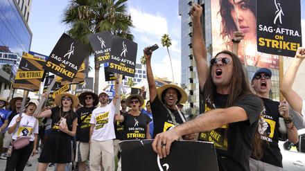 27.09.2023, USA, Los Angeles: SAG-AFTRA-Mitglied John Schmitt (2.v.r) und weitere Mitglieder tragen Schilder während eines Streiks vor Netflix. 