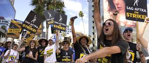 27.09.2023, USA, Los Angeles: SAG-AFTRA-Mitglied John Schmitt (2.v.r) und weitere Mitglieder tragen Schilder während eines Streiks vor Netflix. 